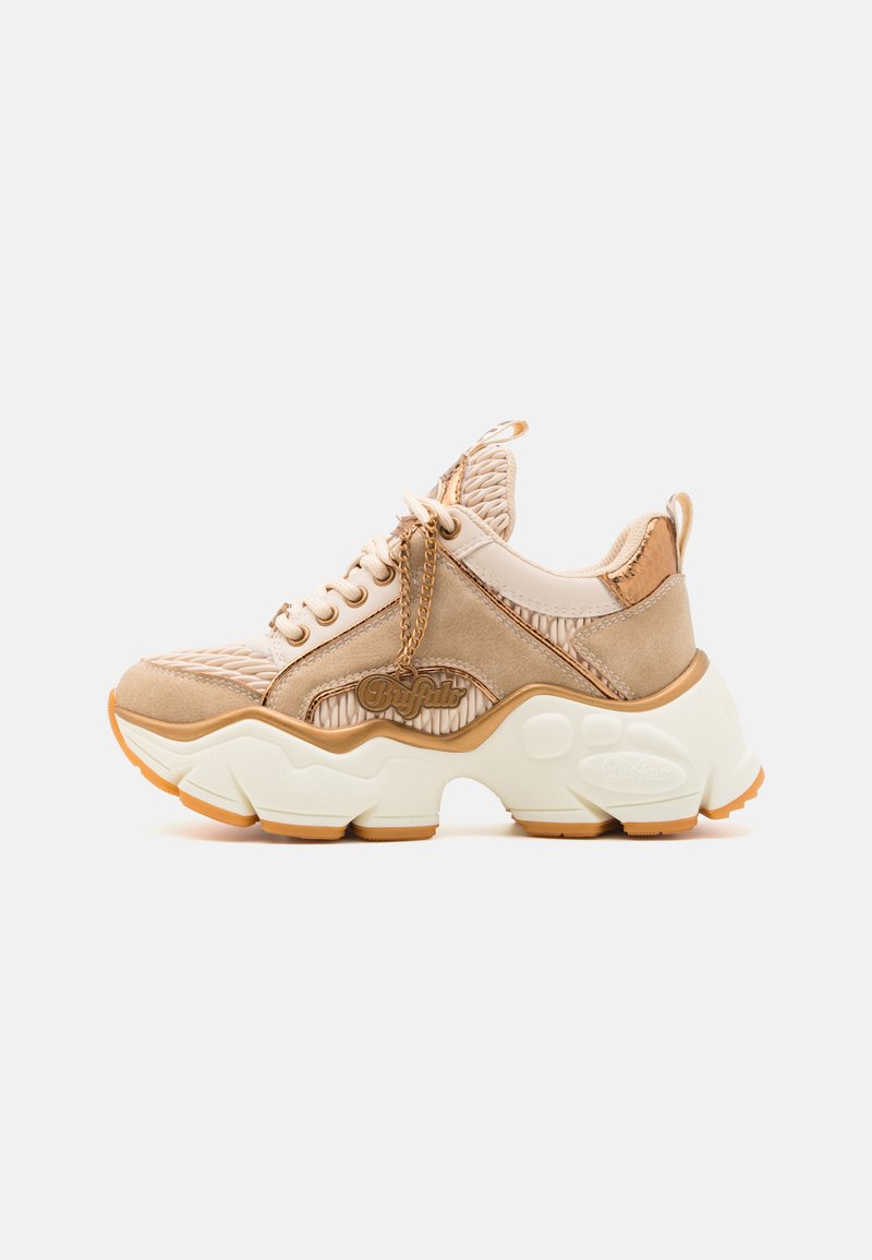 Beige sneakers with textured upper, padded collar, and thick white sole. Features lace-up design, chain detail, and logo accent.
