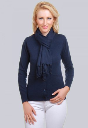 Cardigan marine à fermeture par boutons, à manches longues et avec poches latérales. Écharpe douce de couleur assortie avec des détails frangés.
