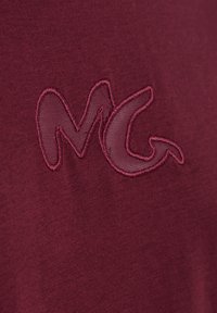 T-shirt in cotone bordeaux con logo "MG" ricamato in una tonalità leggermente più chiara, dalla texture liscia e senza ulteriori motivi.