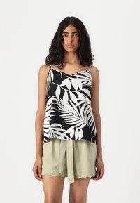 Débardeur noir et blanc à motif de feuilles tropicales avec des bretelles fines, associé à un short vert clair avec des détails en dentelle et une taille nouée.