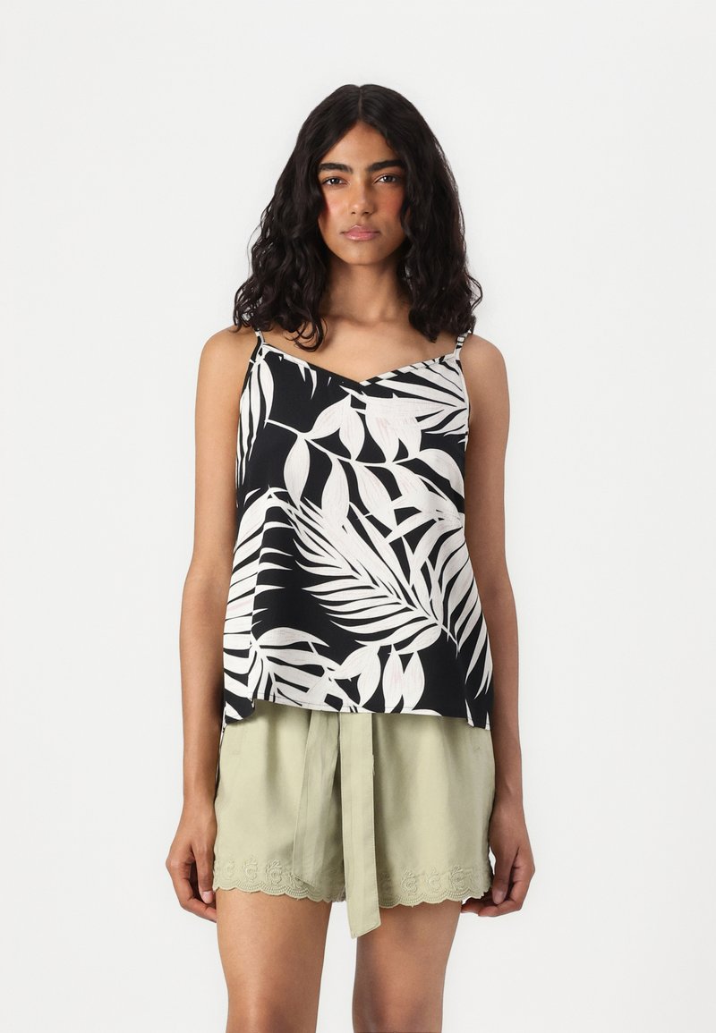 Débardeur noir et blanc à motif de feuilles tropicales avec des bretelles fines, associé à un short vert clair avec des détails en dentelle et une taille nouée.
