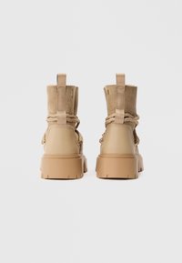 Καφέ ankle boots με σχέδιο από μικτά υλικά, σουέτ επάνω μέρος και ελαστική σόλα, διακοσμητικά κορδόνια και πίσω ταινίες για εύκολη φόρεση.