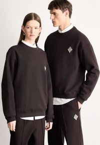 Μαύρα υπερμεγέθη φούτερ και ταιριαστό παντελόνι, με λευκό διαμαντένιο λογότυπο· απαλό ύφασμα, ριμπ μανσέτες και σχέδιο με στρογγυλή λαιμόκοψη.