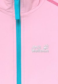 Ljusrosa fleecejacka med en blå dragkedja och en silvrig Jack Wolfskin-logotyp, med röda detaljer vid axelsömmen.