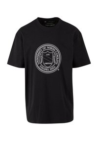 Musta puuvillapaita, jossa on pyöreä valkoinen logo, jossa lukee "North Carolinan yliopisto" ja "Chapel Hill" -teksti, sekä soihtien muotoilu.