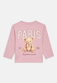 Camisa de manga longa rosa com um urso de pelúcia a usar uma gravata-borboleta, grande texto "PARIS" acima, e frases "BOM TEMPO", "ÓTIMOS LUGARES" e "Acredita sempre em ti."