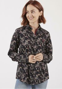 Chemise noire à manches longues avec un motif floral, design à boutons et col. Fabriquée en matériau doux avec des accents décoratifs sur le tissu.