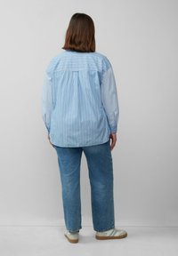 Gestreiftes blaues Hemd mit lässiger Passform, mit langen Ärmeln, einem Rückenpasse und hellfarbigen Jeans aus Denim. Strukturierter Stoff.