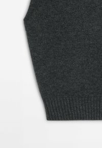 Tummanharmaa neuleliivi, jossa on ribbireunus, pehmeä pinta ja kulmikkaat kainaloaukot. Materiaali näyttää mukavalta ja kevyeltä.