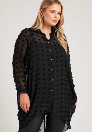 Black sheer blouse with textured floral accents, button-down front, long sleeves, and high-low hem. Soft material with a flowing shape.
