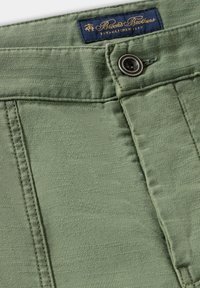 Olivově zelené kalhoty vyrobené z lehkého materiálu. Obsahují zapínání na knoflík, šité detaily a značkovou námořnickou etiketu se zlatým textem.