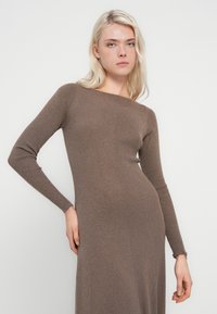 Vestido marrón de punto acanalado con mangas largas, diseño ajustado, cuello redondo y textura suave y elástica. Adecuado para diversas ocasiones.