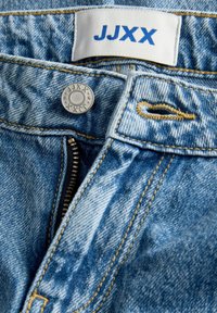 Ανοιχτό μπλε τζιν παντελόνι με ορατό φερμουάρ και μεταλλικό κουμπί κλεισίματος, με ραφές λεπτομέρειες και ετικέτα μάρκας σε άσπρο και μπλε.