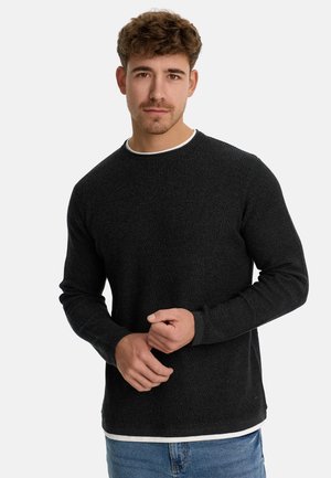 Black textured sweater with long sleeves and a crew neck, featuring a subtle ribbed design and layered white shirt hem underneath.