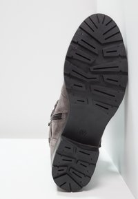 Grey suede ankle boot with zipper detail, featuring a textured black rubber sole and a sturdy tread pattern for grip and durability.