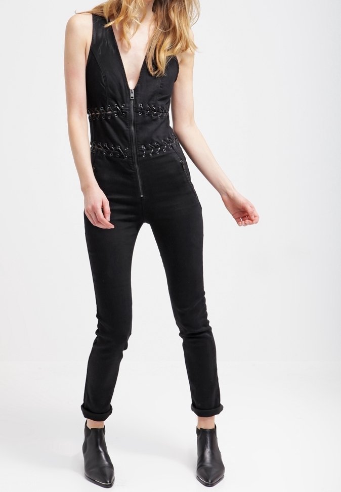 Mono negro con escote en V profundo, cierre de cremallera frontal y laterales con cordones. Diseñado con una silueta ajustada y piernas acampanadas, con puños enrollados.