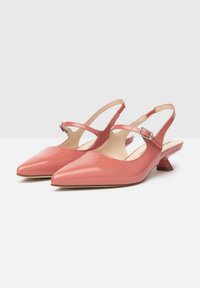 Escarpins en cuir verni rose avec un bout pointu, un petit talon carré et une fine bride réglable avec boucle métallique.