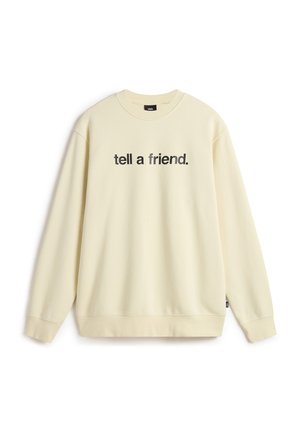 Cream-colored sweatshirt with long sleeves, crew neck, and front text reading "tell a friend." Soft fabric with a relaxed fit.