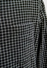 Tela de cuadros en blanco y negro con una textura tejida, que muestra un patrón de rejilla de líneas y cuadrados que se entrecruzan.