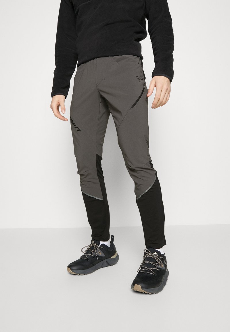 Gray athletic pants with black accents, featuring a tapered fit, zippered pockets, and reflective details along the sides.