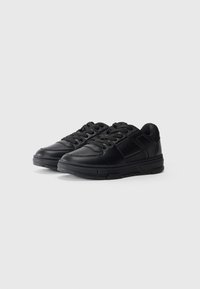 Black sneakers with a smooth leather upper, perforated toe box, flat laces, and cushioned sole. Textured accents and a low-top design.
