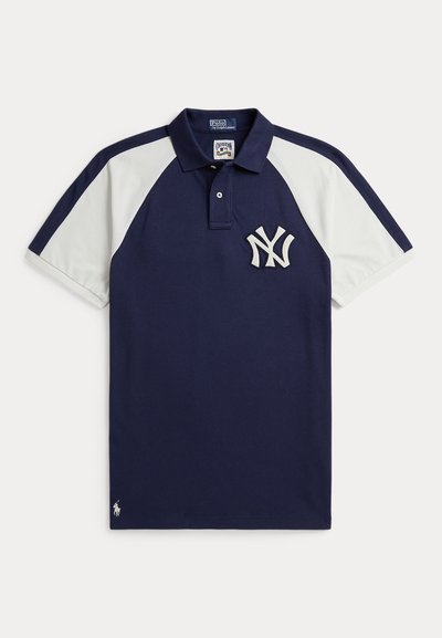 Tumesinine polo-särk valgete raglaanvarrukatega, New York Yankeesi logo rinnal ning väike Polo Ralph Laureni embleem ääre lähedal.
