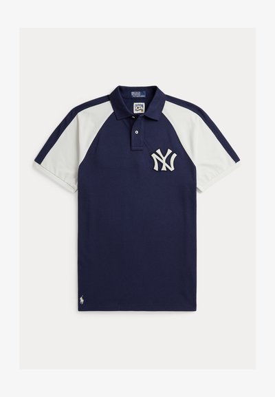 Tumesinine polo-särk valgete raglaanvarrukatega, New York Yankeesi logo rinnal ning väike Polo Ralph Laureni embleem ääre lähedal.