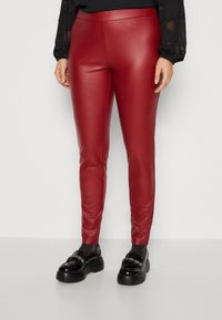 Røde faux læder leggings med et slankt, tætsiddende design. Glat tekstur og ankel længde, parret med sorte platform loafers og glitrende strømper.