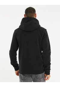 Zwarte fleece hoodie met hoge kraag en trekkoord. Heeft lange mouwen en een ontspannen pasvorm. Zachte textuur, minimale details, geen zichtbare logo's.