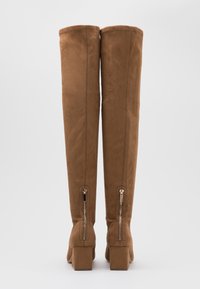 Brown suede over-the-knee boots featuring a block heel, back zippers, and stitching details along the seams. Smooth texture and fitted design.