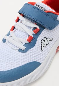 Chaussure de sport blanche avec tige en mesh. Présente des accents bleus et rouges, une sangle réglable et le logo Kappa. Semelle en caoutchouc texturée pour l'adhérence.