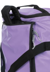 Borsa morbida viola con strap neri, dotata di una tasca con zip, texture liscia e un piccolo manico a loop sulla parte superiore.