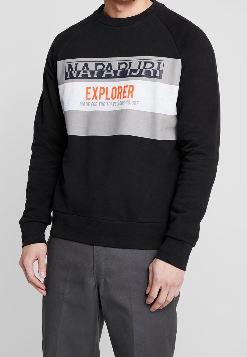 Sudadera negra con rayas horizontales en gris y blanco. Presenta el texto impreso "NAPAPIURI EXPLORER" en colores contrastantes. Mangas raglán, puños de canalé.