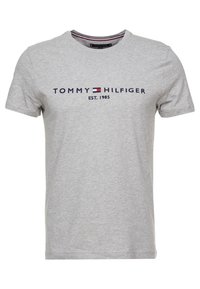 Camiseta de algodón gris con mangas cortas, que presenta un logo azul marino "TOMMY HILFIGER" y "EST. 1985" impresos en el pecho.