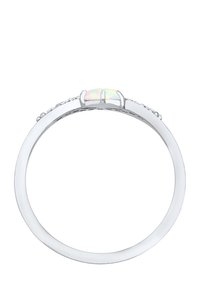 Hvid metalring med en oval opalsten, flankeret af små klare sten, med en glat bånd og poleret finish.