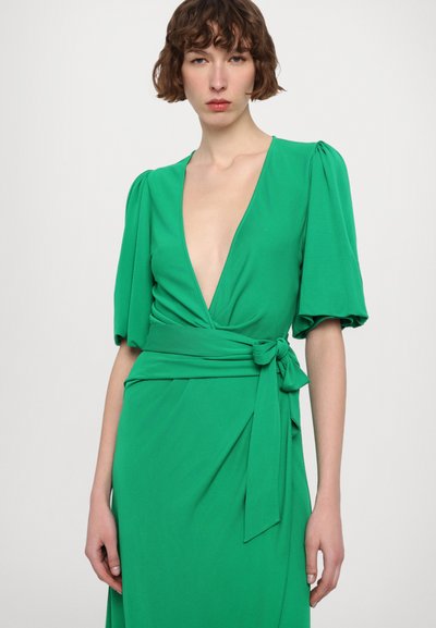 Green wrap dress with plunging neckline and puff sleeves. Features a tied waist belt and flowing fabric texture. Smooth, solid color.