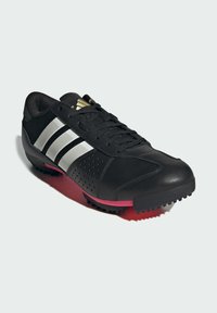 Schwarzer Sportschuh mit silbernen Streifen, pinkem Sohleneinsatz, Schnürung an der Vorderseite und strukturiertem Gummiausgang auf einem weißen Hintergrund.