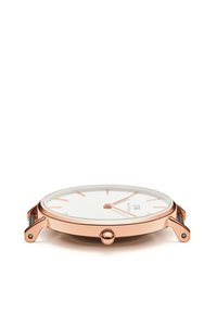 Rose gold watch featuring a white dial, minimalist design, slim case, and a central crown. Pronounced hour markers enhance visibility.