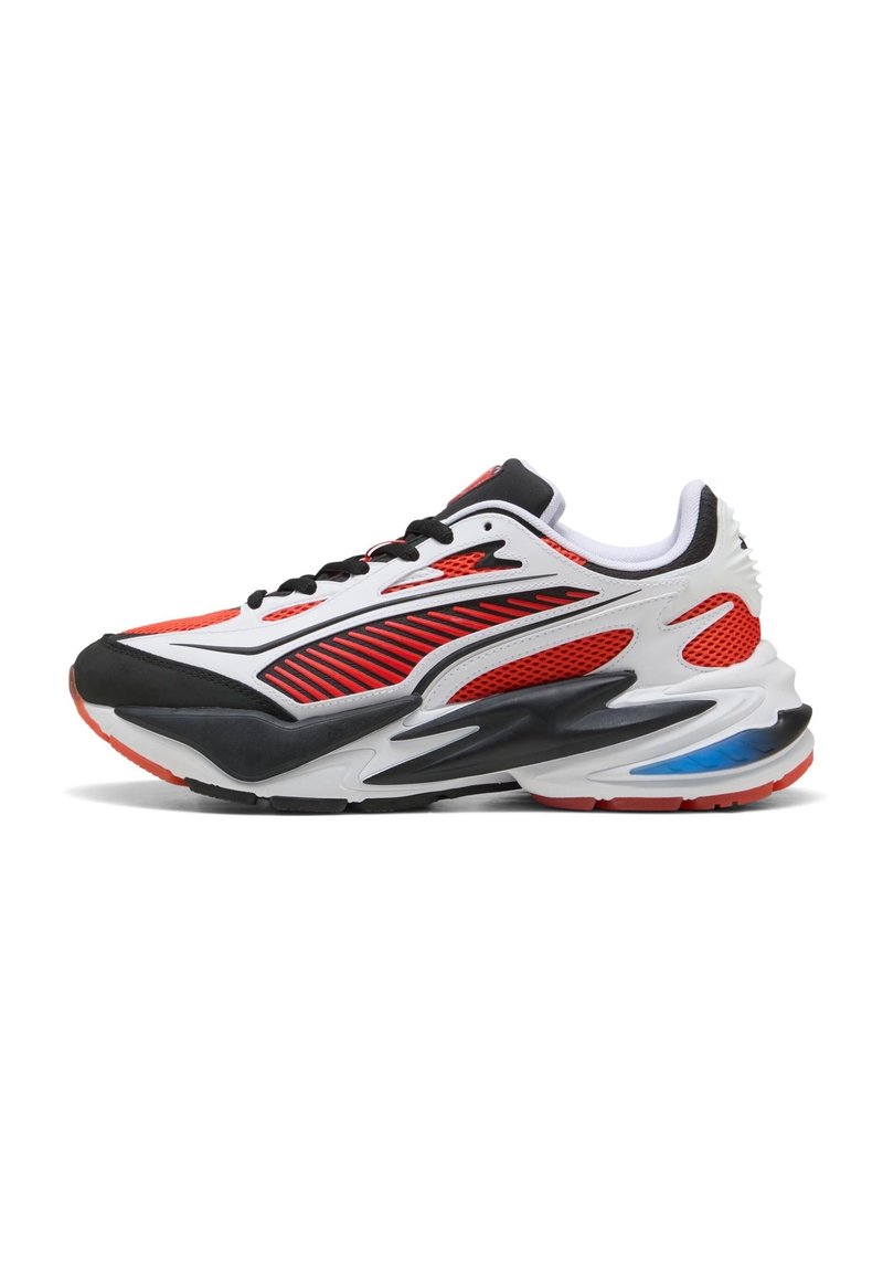 Scarpa sportiva con design rosso, bianco, nero e blu, dotata di pannelli in rete, lacci neri e una suola spessa sagomata.