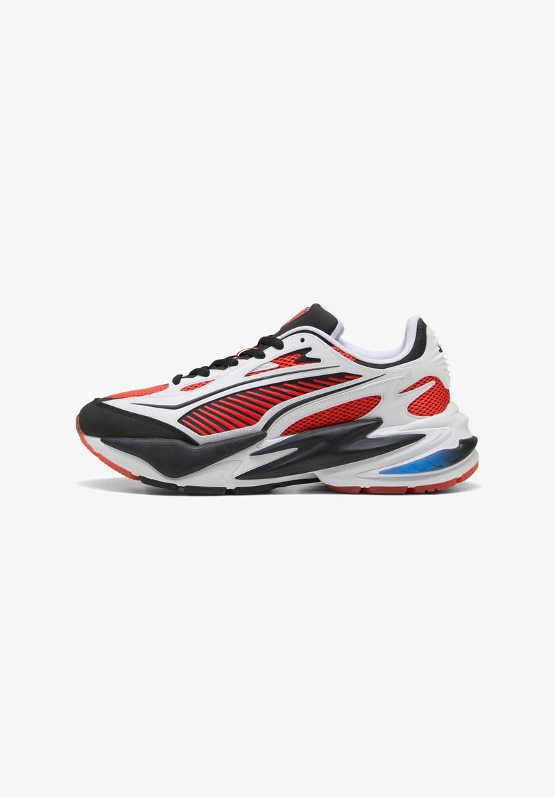 Baskets athlétiques avec un design rouge, blanc, noir et bleu, équipées de panneaux en maille, de lacets noirs et d'une semelle épaisse sculptée.