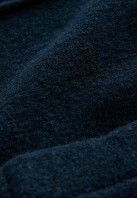 Tessuto blu scuro con una superficie morbida e texture, che presenta una finitura pelosa e soffice e sottili variazioni di ombreggiatura.