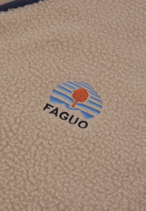 Beige fleece stof met een cirkelvormig logo met blauwe strepen en een oranje boom, vergezeld van de tekst "FAGUO" in het zwart.