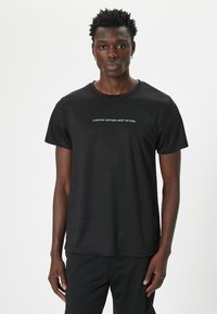Camiseta deportiva negra hecha de tela ligera, con mangas cortas y cuello redondo. El texto en el pecho dice "EDICIÓN LIMITADA MANTENTE ACTIVO."