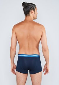 Námořnicky modré boxerky s přiléhavým střihem, zdobené kontrastním světle modrým pasem se dvěma pruhy. Vyrobené z hladké látky.