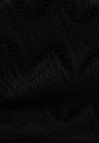 Mustast võrgutatud kangast zigzag- ja teemantmustritega, millel on vahelduvad täismustrilised ja avatud struktuurid.