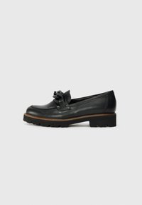 Mocasines de cuero negro con punta redonda, que presentan un detalle decorativo de nudo. Suela de goma negra gruesa con dibujo para un mejor agarre.