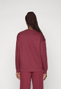 Bordeaux sweatshirt med lange ærmer og rund halsudskæring. Fremstillet af blødt stof, med en afslappet pasform og ribbede manchetter og kant.