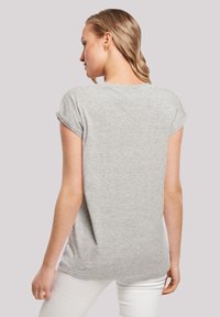 Graues T-Shirt mit kurzen Ärmeln und umgeschlagenen Säumen, weicher Textur, lockerem Schnitt und abgerundetem Saum. Das Modell ist von hinten positioniert.
