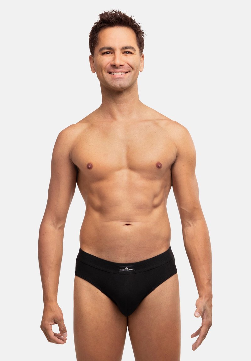 Schwarze Baumwollunterhosen mit elastischem Bund. Das Modell hat eine schlanke Figur und steht vor einem neutralen Hintergrund, um die Unterhosen zu präsentieren.