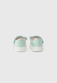 Mintgrønne sneakers med en glitrende overflade, hvide gummisåler og rund form. Har en bageste tab for nem påtagning.